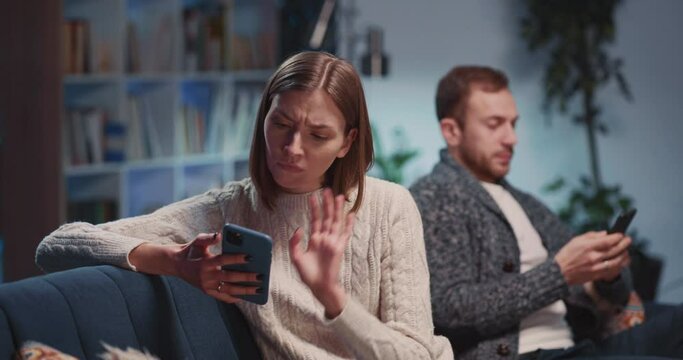 Jealous and angry caucasian couple of boyfriend and girlfriend using mobile phones agruing with each other. Family conflict. RElationship problems.