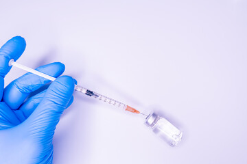 Gloved hand of doctor or nurse holding syringe with liquid vaccine before injecting over white background.Covid19, Coronavirus Concept. Flue shot