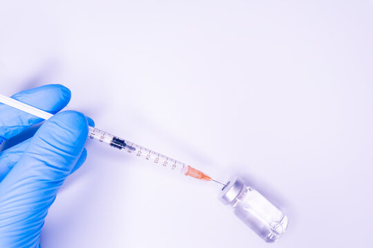 Gloved hand of doctor or nurse holding syringe with liquid vaccine before injecting over white background.Covid19, Coronavirus Concept. Flue shot