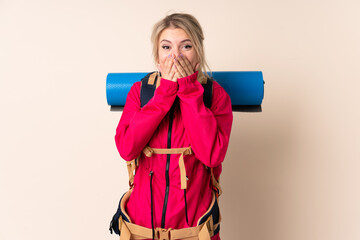 Mountaineer woman with a big backpack over isolated background with surprise facial expression