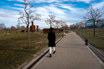 Chica con sombrero y abrigo negro posando en el parque en una tarde de invierno