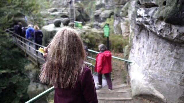 A young girl is walking along a mountain tourist trail. Saxon Switzerland National Park. Geological region. Unique mountainous landscape. National Park of Germany. Huge rocky massif Bastei 