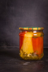Jar of canned sweet bell peppers on black background with copy space