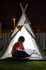 Little kid reading a book on a indian tent at night © Victor