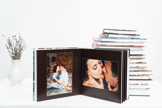 a stack of books. open photobook from photo shoots of a beautiful happy couple
