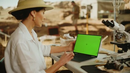 Archeological Digging Site: Female Archaeologist Using Green Screen Chroma Key Display Laptop, Analysing Fossil Remains, Ancient Civilization Culture Artifacts. Historians work on Excavation Site