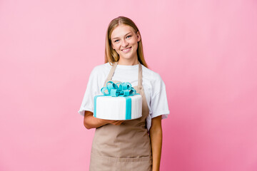 Young russian baker woman holding a delicious cake happy, smiling and cheerful.