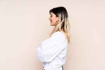 Teenager girl isolated on beige background in lateral position