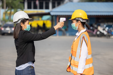 Manager Checking Engineer Worker Body Temperature For Covid19 Virus with Infrared Thermometer Gun at the Working Site