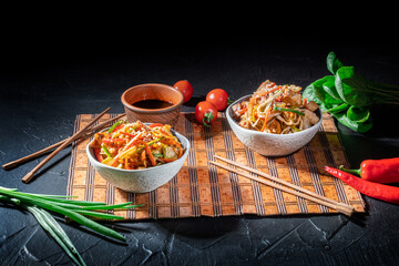 Udon noodles with fried chicken, shrimps (prawns) and vegetables on dark background