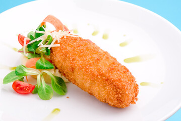fish stick, tomatoes and salad on a white plate. close-up. 