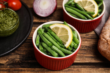 Raw green beans with lemon on wooden table, closeup