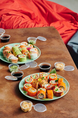 Sushi set on table in office. Party of friends eating sushi rolls using bamboo sticks. Corporate