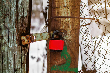 Red padlock on a broken poor gate