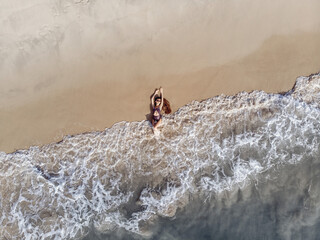 Top view of a slender lovely model in a purple bikini . Hot beach with cool waves. Summer and festive concept, seascape with a girl, beach, beautiful waves, blue water. Top view with drone shot.
