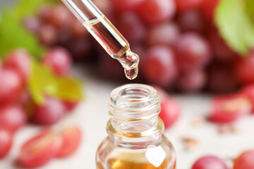 Natural grape seed oil dripping from pipette into bottle, closeup. Organic cosmetic