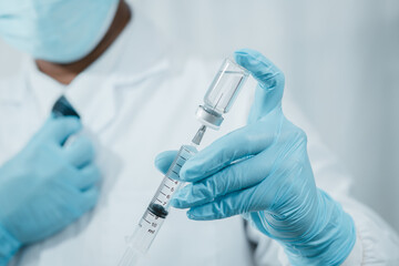 A doctor or scientist in the COVID-19 medical vaccine research and development laboratory holds a syringe with a liquid vaccine to study and analyze antibody samples for the patient.