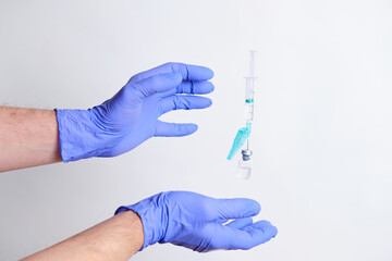 Surgical gloved hands pointing and ready to pick up and use the syringe with the vaccine