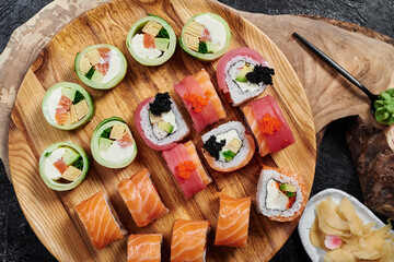 Sushi set with Philadelphia, roll with avocado and roll with tuna on round wooden board on dark background. Close-up. Top view 