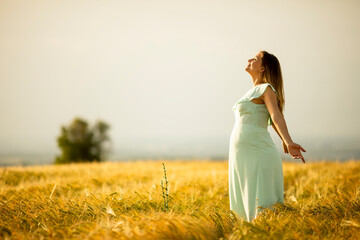 Young pregnant woman in white dress relaxing outside in nature