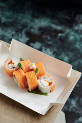 roll filadelfia in disposable kraft paper box on a blue oxidation background. Concept delivery service. Japan food in eco container. Zero waste packaging