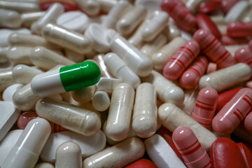 Colorful pills in red and white shades with a green detail. Capsules and tablets macro, medicine and health background.