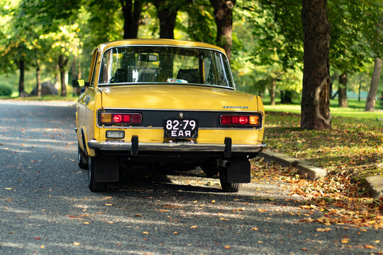Tallinn, Estonia, 26.09.2020: Yellow vintage AZLK Moskvich 2140 car rear side view with black Soviet license plate on the autumn park street with right turn indication light signal blinking