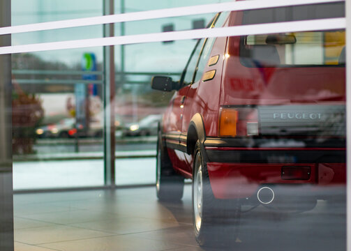 Tallinn, Estonia, 27.12.2020: The rear side of a beautiful red Peugeot 205 GTI retro car partially visible through the display window in a dealership