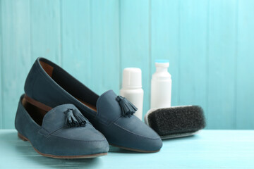 Stylish footwear with shoe care accessories on light blue wooden table
