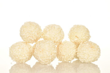 Several round sweets with coconut flakes, close-up, isolated on white.