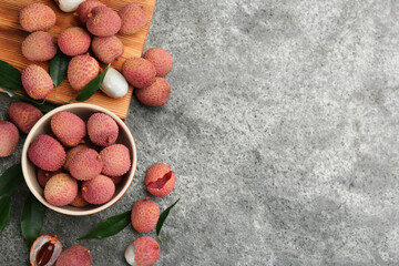Fresh ripe lychee fruits on grey table, flat lay. Space for text