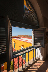 Obraz premium Cuba, Trinidad, window over plaza, shutters and shadows. Trinidad and the Valley de los Ingenios is a UNESCO World Heritage Site.