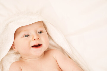 Cute small boy lying at bed. Childhood bath concept. Light background. Smiling child. Happy...