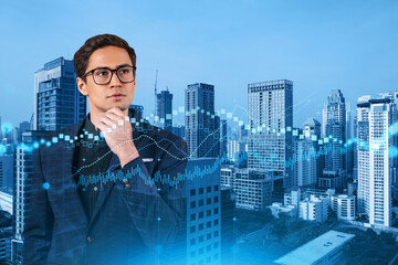 A young eastern handsome trader and stock market analyst in suit dreaming about market behavior and forecast in crisis. Trading at corporate finance fund. Forex chart. Bangkok. Double exposure.