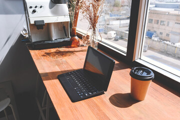 Work area with laptop and coffee near the window.
