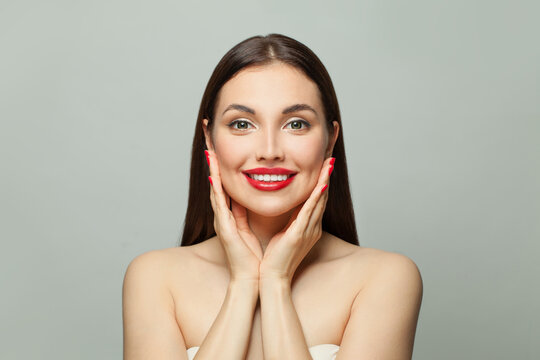 Attractive woman with red manicured nails smiling on white. Body care and manicure concept