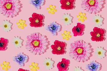 Creative pattern made with bright yellow, rose, red, purple, white and dark blue flowers on pastel pink background. 80s or 90s retro fashion aesthetic spring idea. Mothers or woman day romantic idea. 
