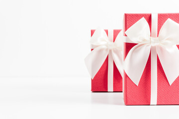 Two pink gifts with white satin bow on white table. Front view. Place for text, copy space, mockup