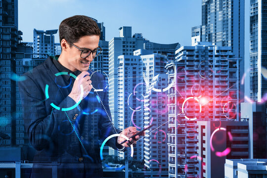 A handsome eastern businessman trying to achieve tremendous growth in commerce using new technological approaches by researching the internet in smartphone. Tech hologram icons over Bangkok