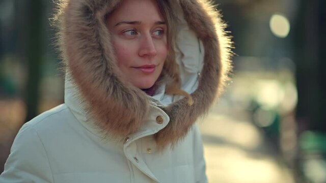 Happy woman wearing white winter coat  resting outside in the sun