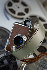 vintage movie camera lies against the background of reels with developed film of lenses.