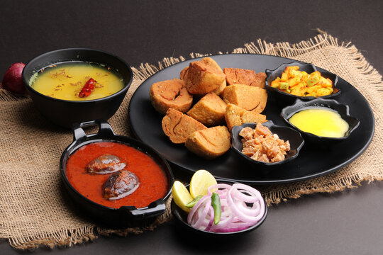 bafle or bati is popular main course dish in India served with dal daal brinjal curry jaggery gud and clarified butter or ghee