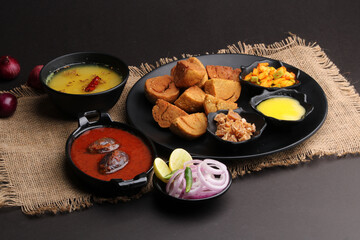 bafle or bati is popular main course dish in India served with dal daal brinjal curry jaggery gud and clarified butter or ghee