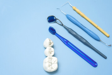 Artificial teeth with caries and toothbrush with dental tools lie on a blue background