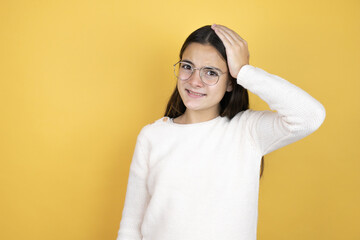 Beautiful child girl wearing casual clothes putting one hand on her head smiling like she had...