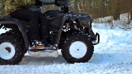 Fototapeta na wymiar blurred motion of wheels of quattro bike riding on snowy forest road on a winter day