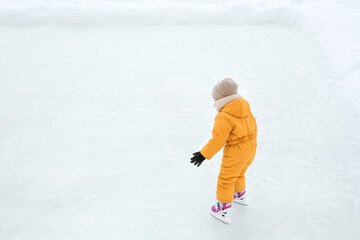 Fototapeta na wymiar A girl learns to skate. A child rides on ice on a frozen lake. A frosty winter day. Figure skating lessons. copy space.