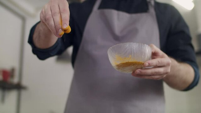 A young chef adds spices to the dish. 