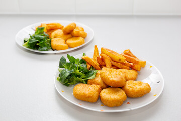 Chicken nuggets with french fries and salad for kids menu.