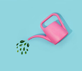 Pink flower watering can with green leaf drops. Pastel blue background. Spring concept.